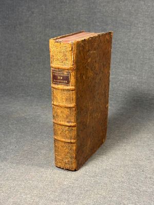 an old book sitting on top of a table on a gray surface