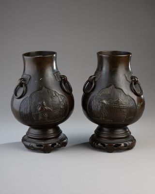pair of bronze vases sitting on top of a table