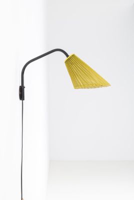 a yellow lamp on a white table next to a white wall