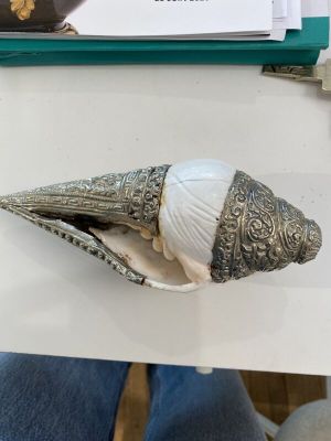 une coquille argentée renfermant une coquille blanche, posée sur une table