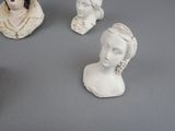 four busturines of women on display on a gray surface
