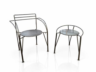 pair of metal chairs with a glass top on a white surface