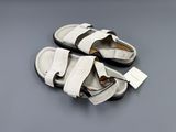 white and black sandals on a gray surface with a tag