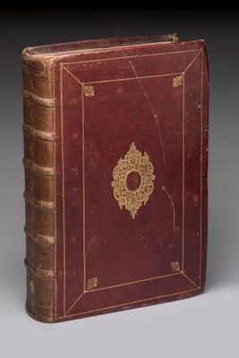 un vieux livre rouge orné d'un médaillon doré sur la couverture