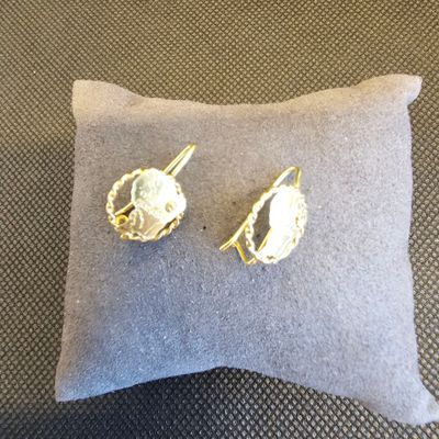 une paire de boucles d'oreilles posée sur un oreiller, lui-même posé sur un autre oreiller