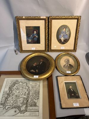 plusieurs portraits d'hommes et de femmes, encadrés ou non, posés sur une table