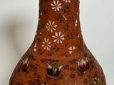 a brown vase with flowers on it sitting on a white surface