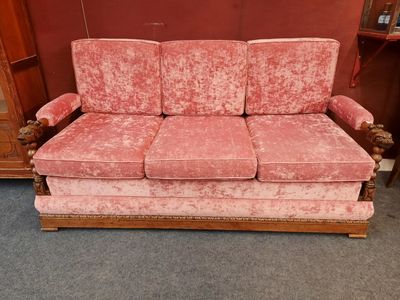 une photo d'un canapé rose posé dans une pièce, à côté d'une commode