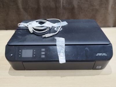 a black printer sitting on top of a wooden table next to a charger