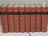 six red books are lined up on a white surface
