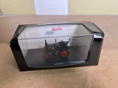 a toy tractor in a clear box on a table