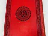 an old red book sitting on top of a white table