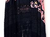 pink and black shawl with flowers and fringes hanging on a wall