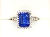 a close up of a blue sapphire and diamond ring on a white surface