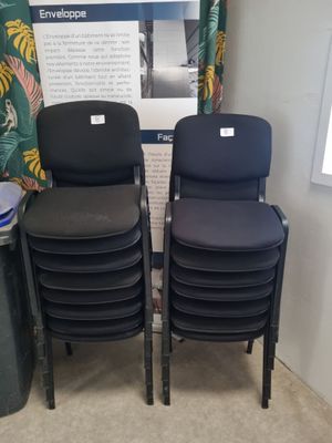 Deux chaises noires sont placées l'une à côté de l'autre devant une affiche