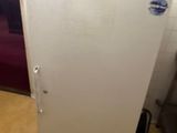 a white refrigerator sitting in a kitchen next to a chair