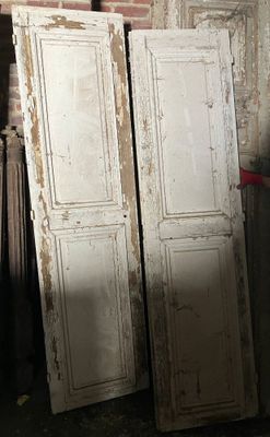 deux vieilles portes blanches adossées à un mur de briques