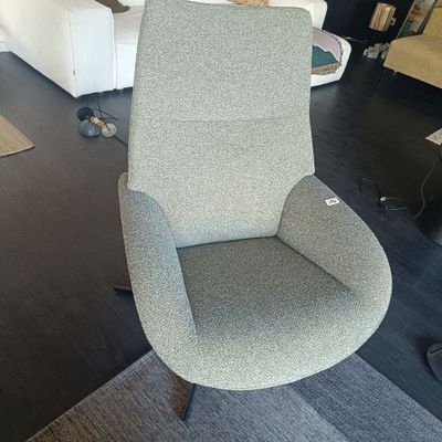 une chaise grise placée dans un salon, à côté d'un canapé blanc