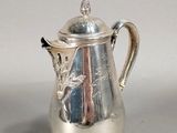 une cafetière en argent avec un couvercle, posée sur une table