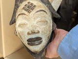 a person holding a wooden mask in their hand