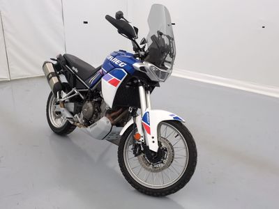 une moto garée dans une pièce aux murs et au sol blancs