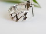 sterling silver ring with a diamond cut design on a white surface