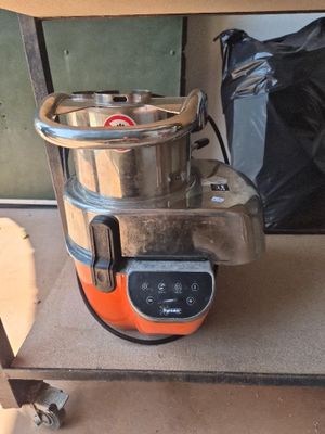 un mixeur orange et noir posé sur une étagère à côté d'un sac noir