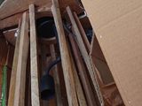 a pile of wooden chairs in a room with a cardboard box on the floor