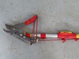 a red and yellow pipe cutter laying on the floor