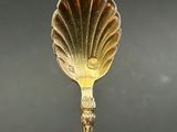 a gold spoon with a shell shaped handle on a table