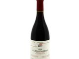 the bottle of red wine is sitting on a white surface