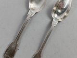 two silver spoons sitting on top of a table next to each other