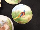 three plates with birds painted on them sitting on a table