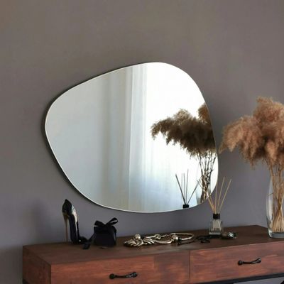 a mirror on the wall above a table with a vase of flowers