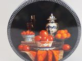 a plate with a picture of a bowl of oranges and a vase on it