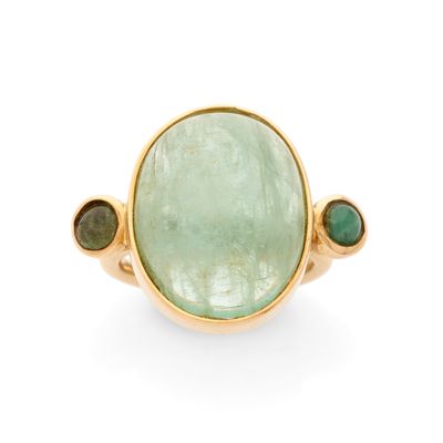 un gros plan d'une bague ornée d'une pierre verte entourée de pierres vertes