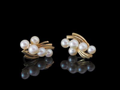 deux paires de boucles d'oreilles en perles et en or posées sur un fond noir