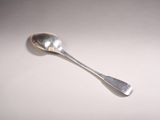 une cuillère en argent avec un manche de cuillère sur une surface blanche