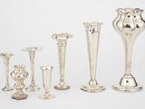 cinq vases en argent et un bougeoir posés sur une table