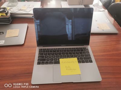 a laptop computer sitting on a desk with a sticky note on the screen