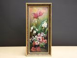 tableau représentant des fleurs, dans un cadre doré, posé sur une table