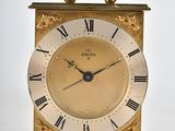 a gold clock with roman numerals on the face