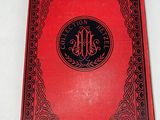 a red book with a black border and a monogram on it
