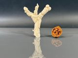 une petite figurine blanche posée à côté d'une noix à moitié mangée
