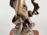 bronze statue of a woman holding a bird on a marble base
