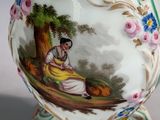 a vase with a painting on it sitting on a table