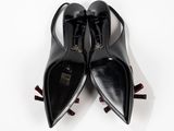 pair of black leather shoes with red bows on a white surface