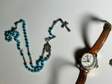 a watch and a necklace on a white surface