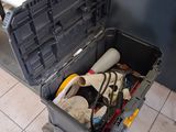 une boîte à outils contenant des outils, posée sur un sol carrelé