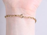 someone is holding a gold chain bracelet with a heart on it